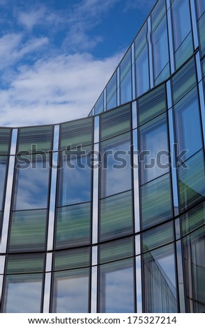 Office building with shiny blue glass and green facade on a sunny day
