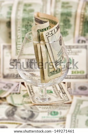 Tip jar (wine glass) containing US dollars with a money background