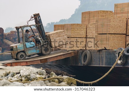 Tawau Sabah Malaysia - September 16, 2015 : Forklift operator stacking piles of timber product onto barge at Tawau port. This port is among international hub for timber export from Sabah Borneo.