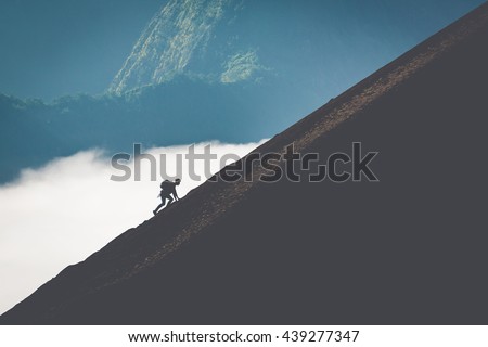 silhouette of man climbing steep mountain. Good image for adventure, struggle and success story photo.