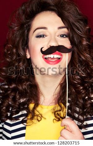 Attractive playful young woman holding mustache on a stick