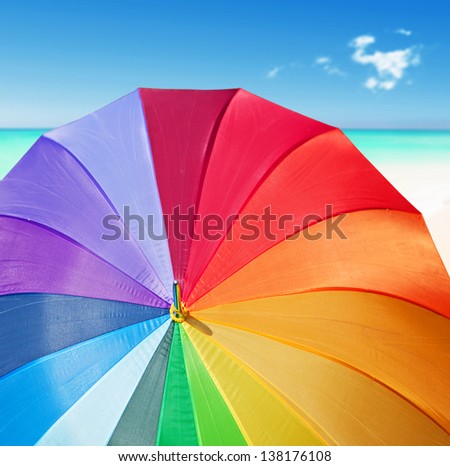 Colorful rainbow umbrella on a tropical beach
