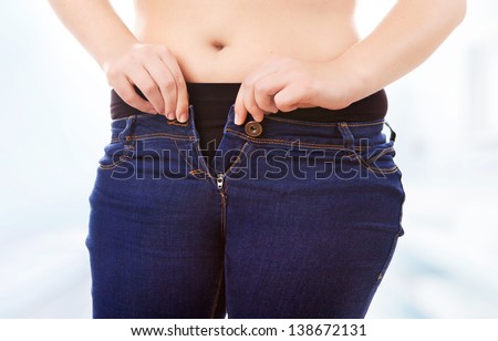Size 40/42 woman zipping tight jeans, obesity and overweight concept