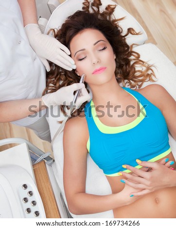 Woman getting face laser treatment in medical spa center