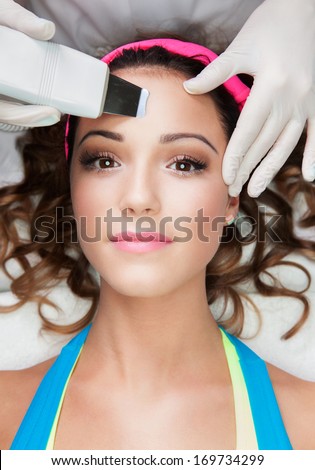 Woman getting laser face treatment in medical spa center