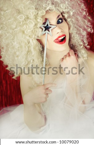 Beautiful smiling blond fairy girl with magic wand, pulling a funny face