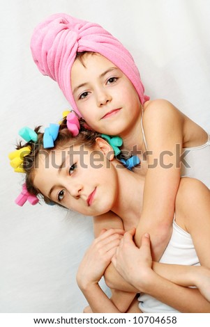 Beauty day of twin sisters - one with a pink towel, other with curlers on her hair. Please check for more.