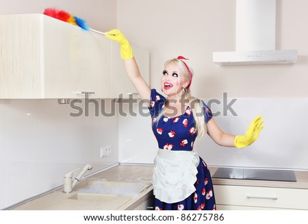 Cheerful housewife is cleaning the kitchen