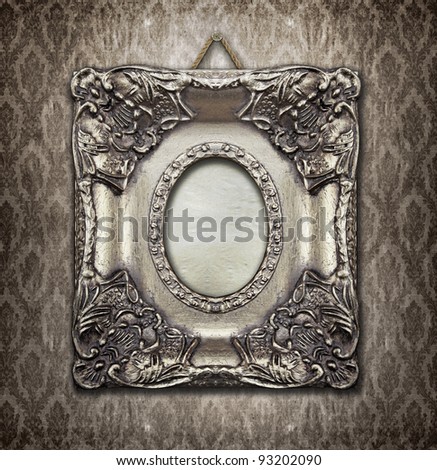 Ornamental silver frame on an aged damask wallpaper