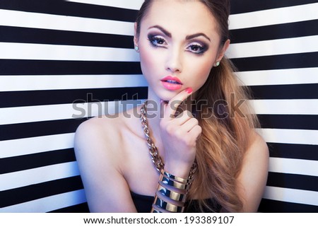 Attractive young woman with eye enlarging make up on stripy background, beauty and fashion concept