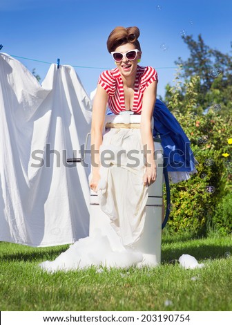 Pin up style photo of woman doing laundry using vintage wringer washing machine