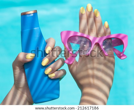 Summer fashion and beauty hand care concept, woman holding sunglasses and sunscreen lotion