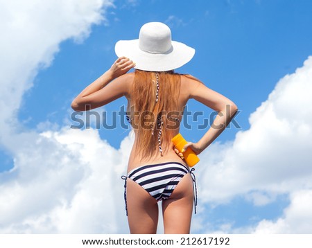 Sun protection and summer body care concept, woman wearing hat and bikini holding sunscreen spf lotion