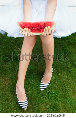 Girl with watermelon sitting on a garden bench