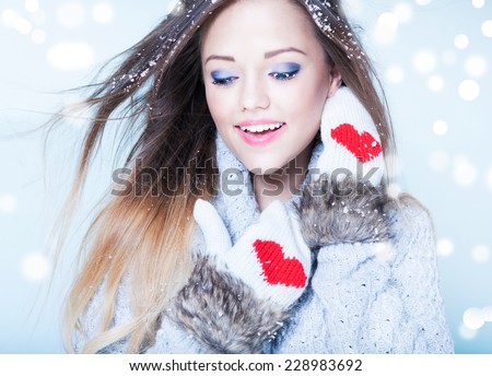 Beautiful happy young woman wearing winter gloves covered with snow flakes. Christmas portrait concept.