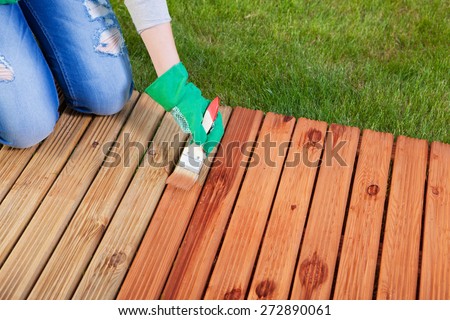 Applying protective varnish on a patio wooden floor, maintenance concept