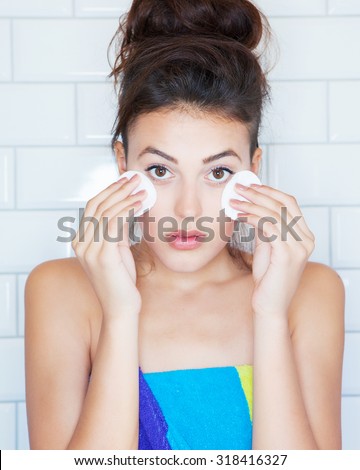 Make up removal concept, young attractive woman covered with towel  with cotton pads