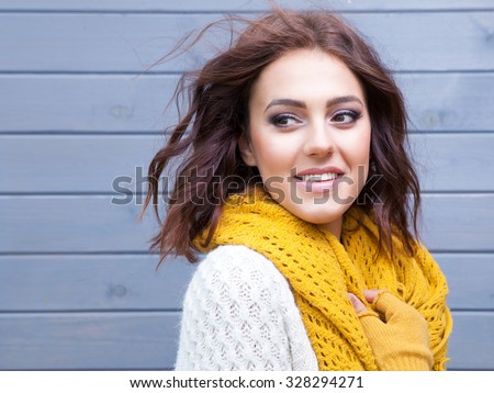 Beautiful natural young smiling brunette woman wearing knitted sweater gloves and scarf. Fall and winter fashion concept.