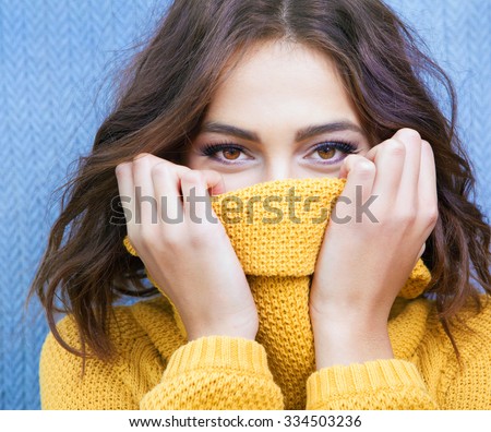 Beautiful natural young shy brunette woman with smiling eyes wearing knitted sweater