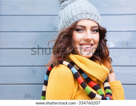 Beautiful natural young smiling brunette woman wearing knitted sweater, leather gloves, scarf and hat. Fall and winter fashion concept.