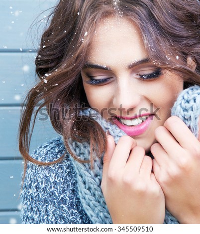 Beautiful natural young brunette smiling woman with eyes closed, wearing knitted scarf, covered with snow flakes. Snowing winter beauty concept