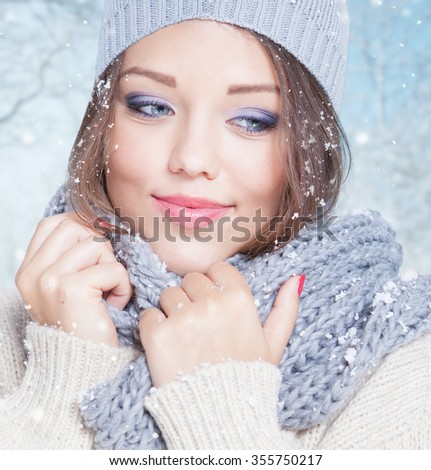 Beautiful happy smiling young woman wearing winter hat covered with snow flakes. Christmas portrait concept. Winter landscape background