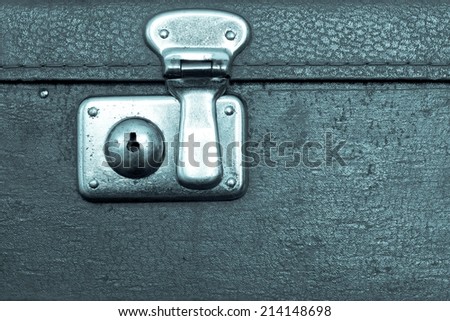 the closed metal rusty lock closeup on part of an old suitcase with the textured leather surface of dark blue color