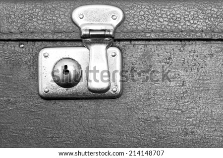 the closed metal rusty lock closeup on part of an old suitcase with the textured leather surface of dark gray color