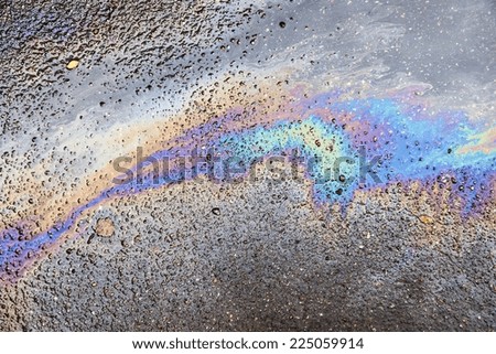 the abstract textured pattern from iridescent spots of oil or gasoline on asphalt