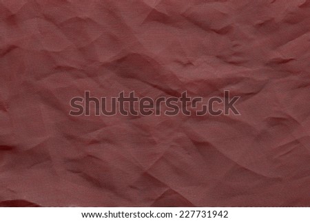 the abstract textured background from crumpled mesh with small cells synthetic fabric of crimson color