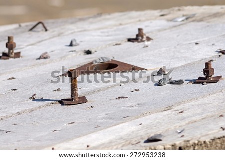 rusty bolts with nuts stick out in wooden boards in an end face of the old coil for a cable