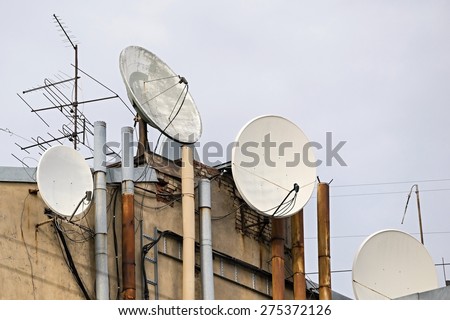 old analog and modern digital satellite antennas are installed on the old house for reception of telecasts