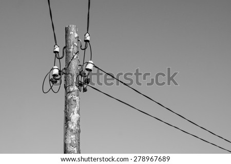 industrial a retro scenery from an old wooden column with electric wires and a cable on ceramic insulators of monochrome gray color