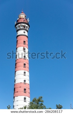 the high building of an old beacon for implementation of navigation of river and sea vessels and background of the blue sky