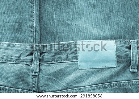 texture of fabric of jeans clothes of indigo color with a leather label for abstract backgrounds and a blank space for the text
