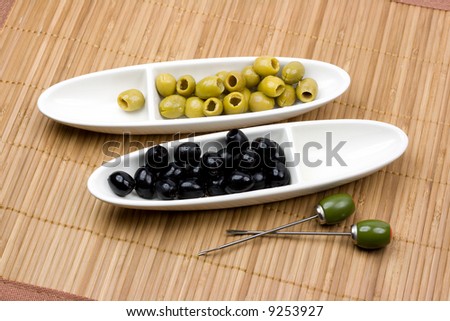 Green and black olives on a white plates