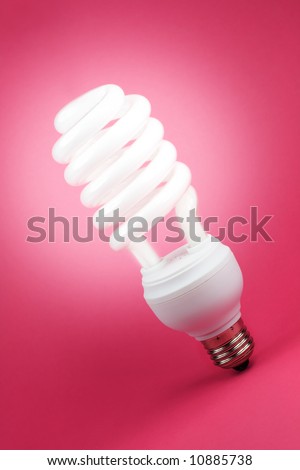 Turned on fluorescent light spiral bulb on pink background