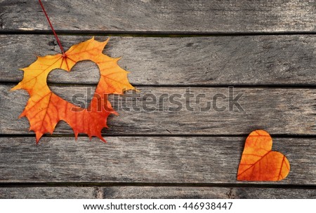 Autumn red and orange leaves with heart.  Fall wooden background.