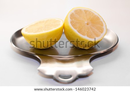 Lemon cut in half with both the inside and zest visible, resting on a silver dish