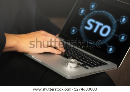 Security Token Offering (STO) text written on a laptop screen held by a business man with a stack of Ethereum