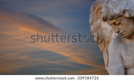 Angel at twilight. Sculpture of an angel at twilight with clouds forming a wing
