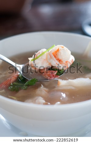 Close up of prawn in bowl of tom yam soup.