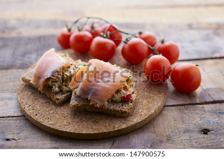 Smoked salmon toast with vegetable coating and cherry tomato. Shallow depth of field.