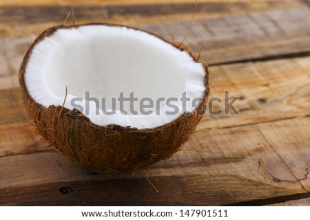 Fresh Coconut. Close up of fresh broken coconut on wooden table. Shallow depth of field.
