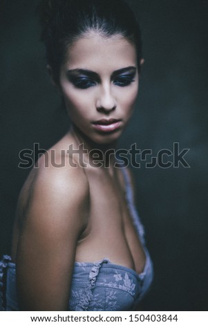 Portrait in blue. Portrait of a beautiful woman showing her femininity and tenderness. Strong grain added. Shallow depth of field.