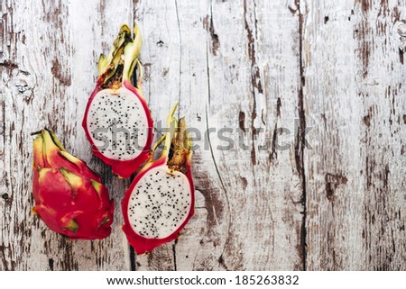 Dragon fruit. Close up cross section of a raw ripe dragon fruit on white wooden table. Soft focus, grain added.