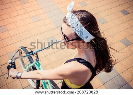 closeup portrait of a stylish girl hipster riding a cruiser bicycle