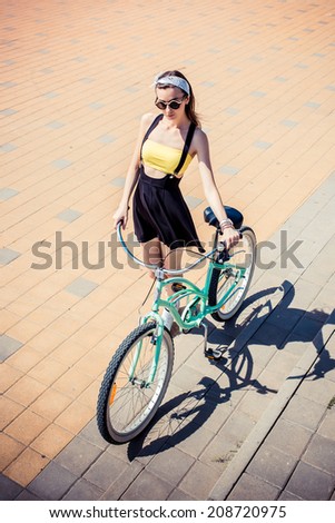 stylish girl hipster posing near cruiser bicycle