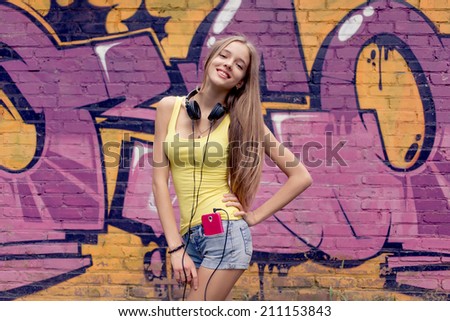 portrait of a teenage girl smiling and posing against wall with graffiti