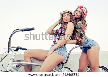 two beautiful girls twins ride on a tandem bike outdoors